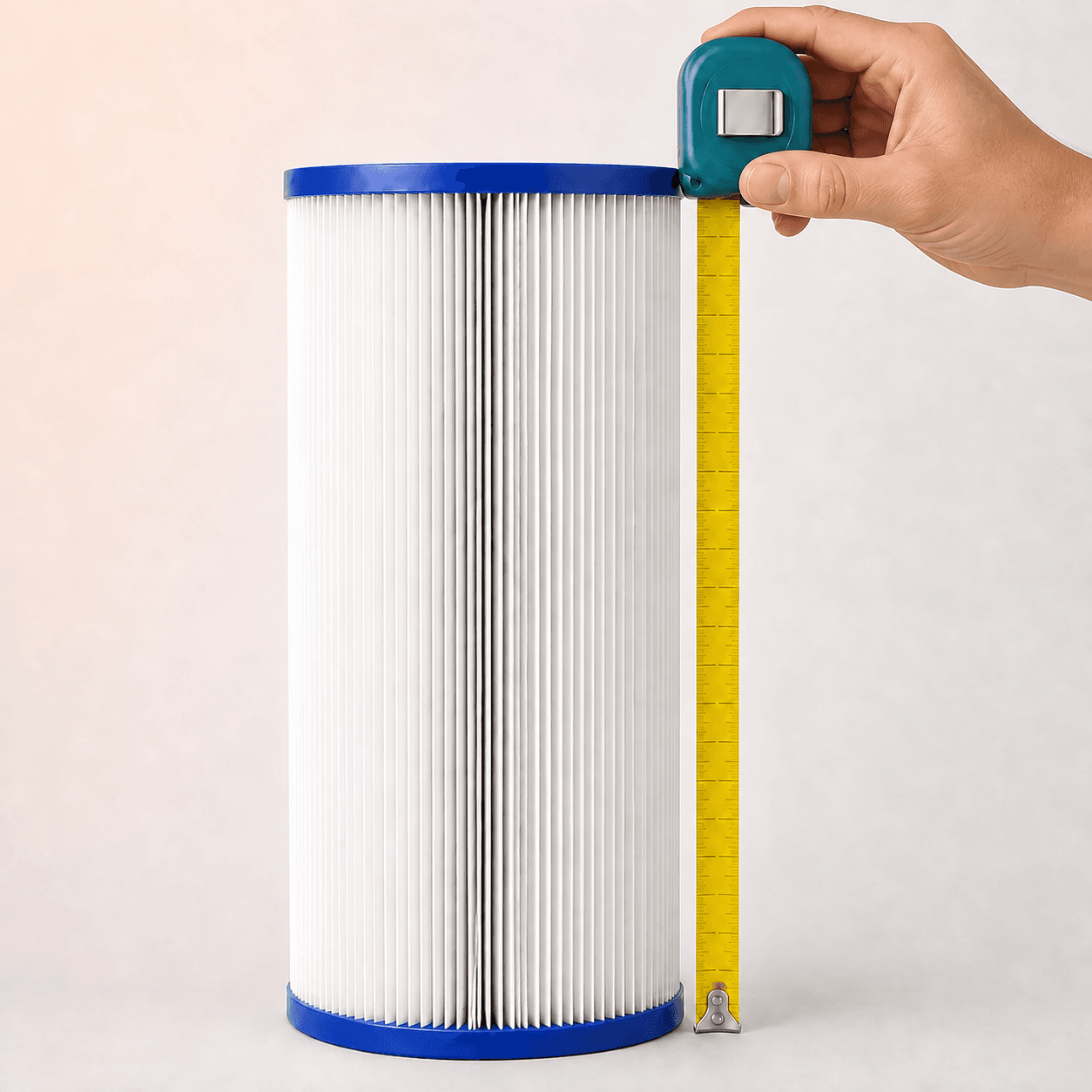 Hand holding the tape-measure case at the top end cap while measuring a pool filter cartridge end to end