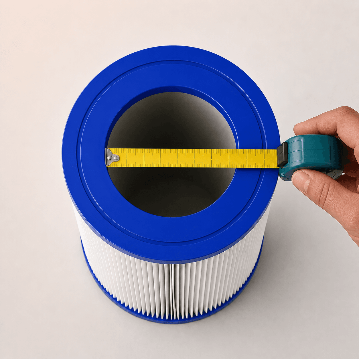 Hand holding a tape measure across the open center hole of a pool filter cartridge