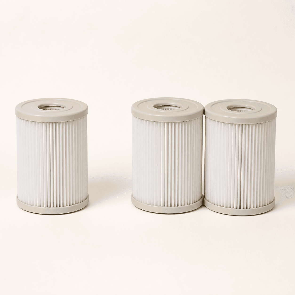 One short spa filter cartridge beside a matching pair of cartridges